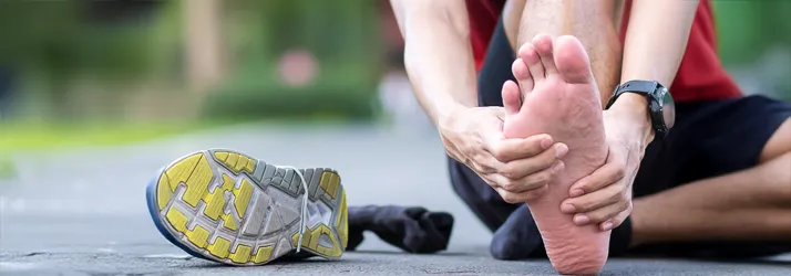 Chiropractic Rock Hill SC Kick Heel Pain To The Curb Man sitting on road with one shoe off rubbing is foot due to foot pain