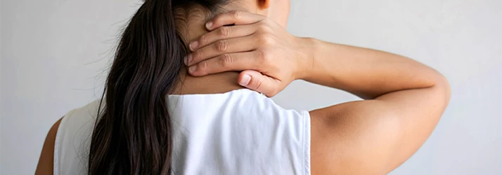 Woman in White Sleeveless Shirt Clutching the Back Of Her Neck In Pain