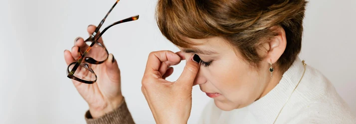 Woman with Short Hair Holding The Bridge of Her Nose Between Her Fingers Wincing in Pain