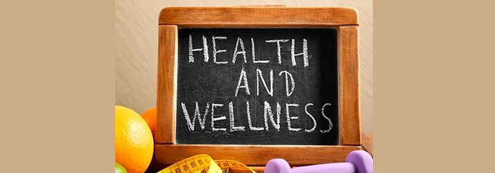 A chalkboard reading “Health and Wellness” with fruits, a measuring tape, and a dumbbell.